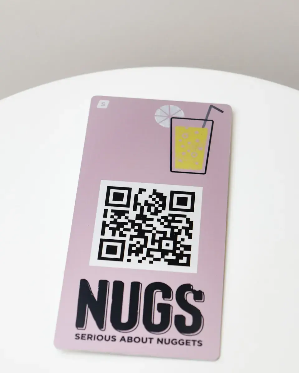 Pink aluminium plate for Nugs with a QR code and drink illustration